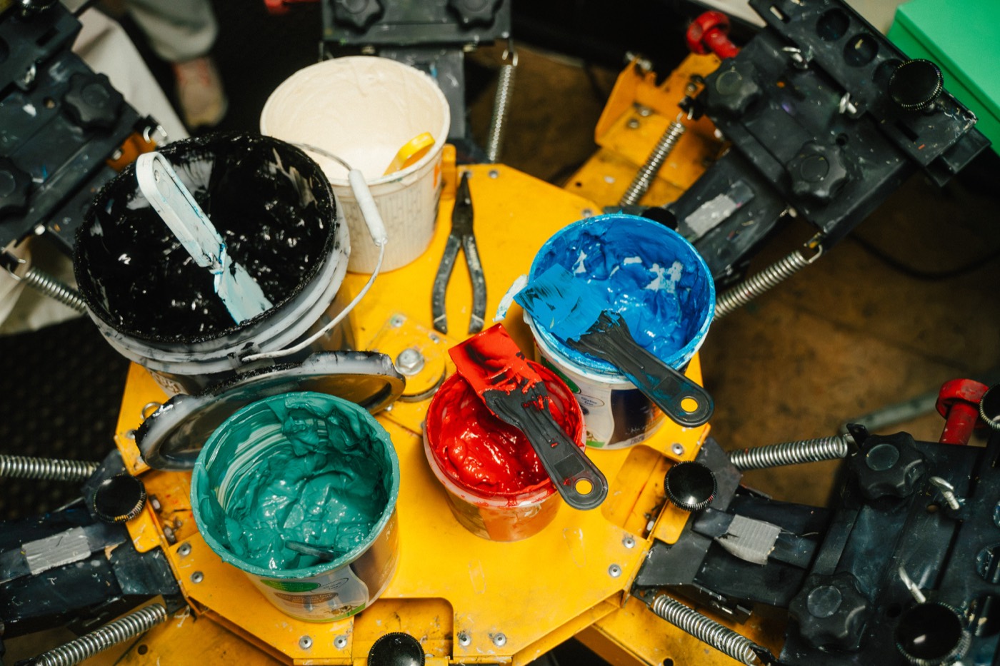 Buckets of ink on the press carousel: teal, red, black and white