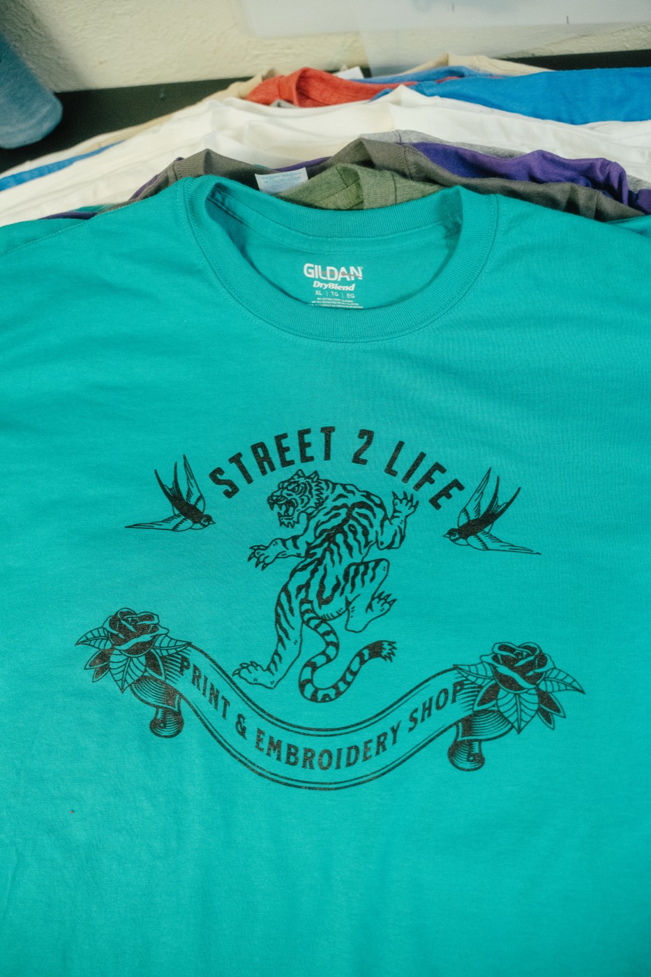 A teal tee with the Street 2 Life tiger print, fresh off the press